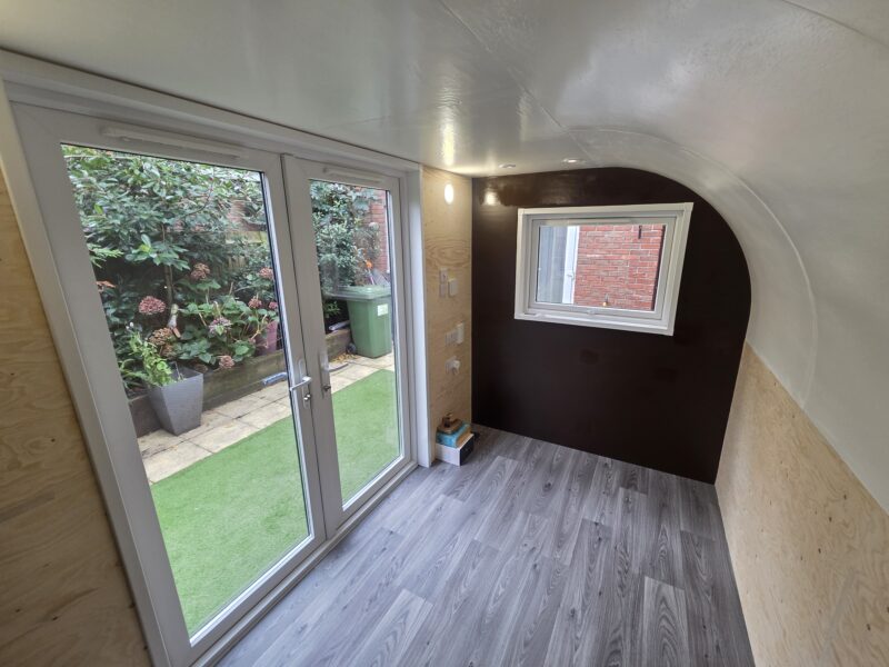 Interior of eSnug Plus garden studio with feature wall, painted ceiling, curved finish, full electrics, and Wi-Fi